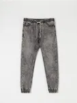 Spodnie jeansowe o kroju jogger uszyte z bawełnianej tkaniny z dodatkim szybkoschnącego materiału oraz elastycznych włókien. - szary