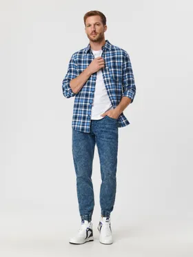 Spodnie jeansowe o kroju jogger uszyte z bawełnianej tkaniny z dodatkim szybkoschnącego materiału oraz elastycznych włókien. - niebieski