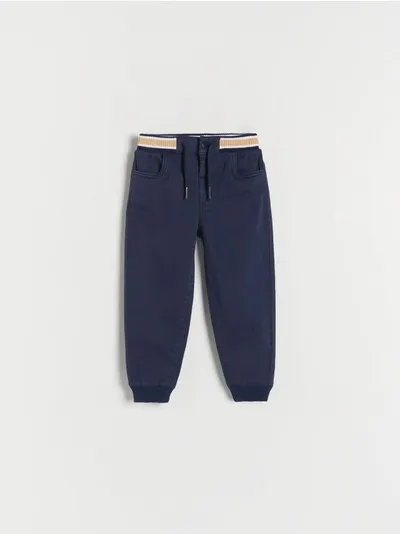 Reserved Spodnie typu jogger, wykonane z bawełnianej tkaniny z dodatkiem elastycznych włókien. - granatowy