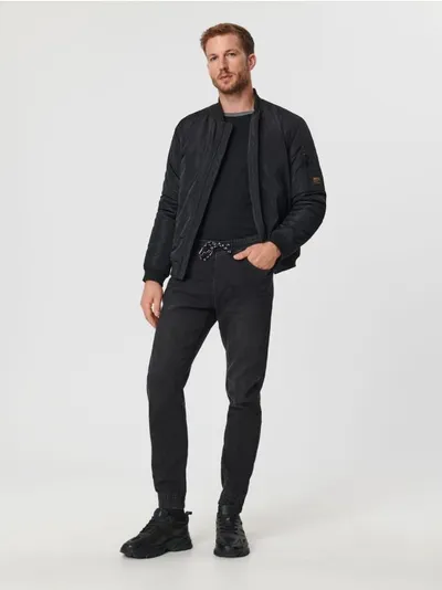 Sinsay Spodnie jeansowe o kroju jogger uszyte z bawełnianej tkaniny z dodatkim szybkoschnącego materiału oraz elastycznych włókien. - czarny