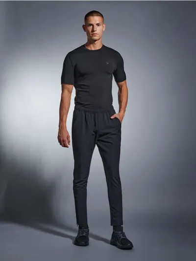 Sinsay Sinsay - Spodnie dresowe SNSY PERFORMANCE - czarny - gumka w pasie,dwie kieszenie,ozdobny nadruk,nogawki z zapięciem - czarny