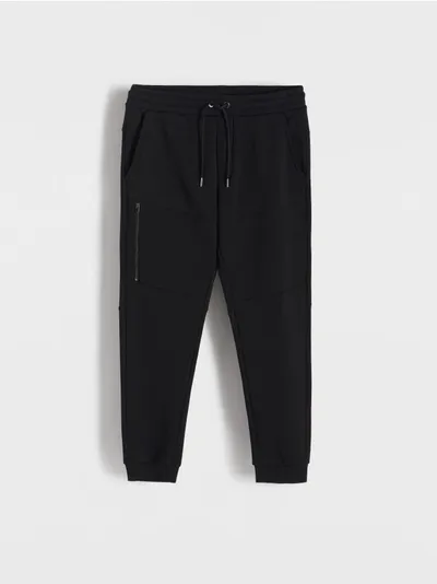 Reserved Spodnie typu jogger o dopasowanym kroju, wykonane z gładkiego materiału z bawełną. - czarny