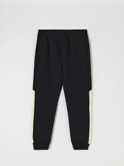 Sinsay Bawełniane spodnie dresowe o kroju regular jogger, wykończone ściągaczami. Łączone kolory na nogawkach. - czarny