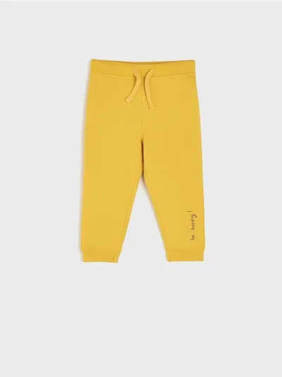 Sinsay Spodnie dresowe o kroju jogger. Ozdobione delikatnym napisem. - żółty