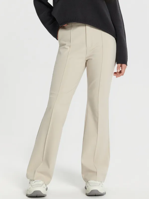 Eleganckie spodnie o kroju flare uszyte z elastycznego, podkreślającego sylwetkę materiału. - kremowy