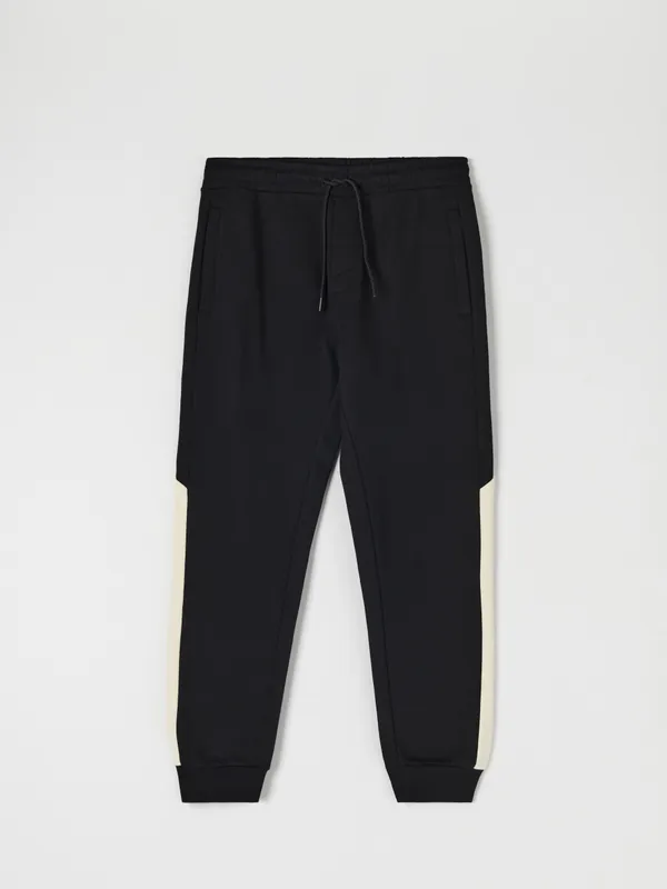 Bawełniane spodnie dresowe o kroju regular jogger, wykończone ściągaczami. Łączone kolory na nogawkach. - czarny