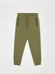 Bawełniane spodnie dresowe o kroju regular jogger z ozdobnymi przeszyciami. - zielony